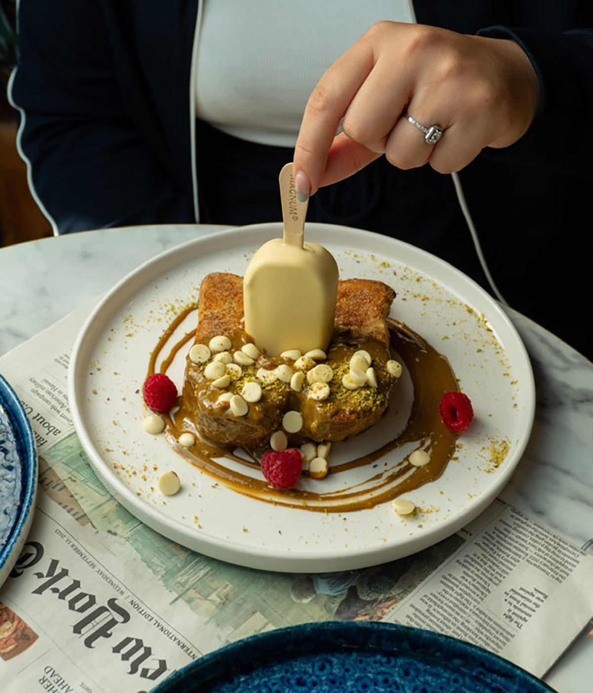 Frenchtoast im „Cloud Kitchen“ auf weißem Teller, garniert mit Nüssen, Himbeeren und einem halben Magnum Mini White das im Frenchtoast steckt.