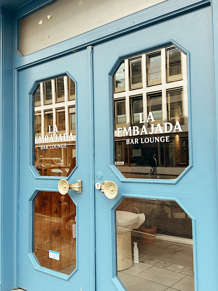 Eine blaue Eingangstür führt ins La Embajada