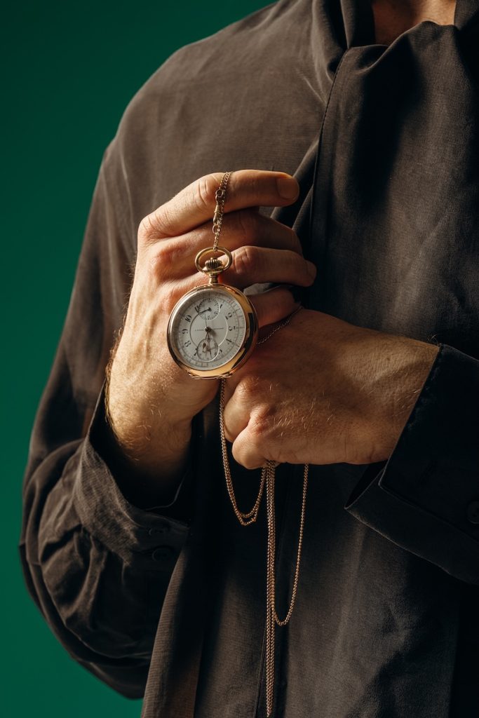 Mann hält goldene Taschenuhr mit Kette in der Hand, Ausstellung „Zier & Zeichen“ im Landesmuseum Württemberg.