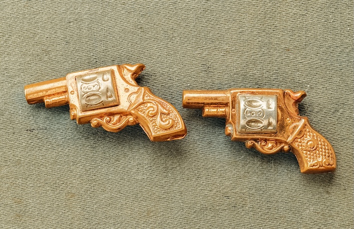 Zwei goldene Manschettenknöpfe in Form von Trommelrevolvern, um 1900.